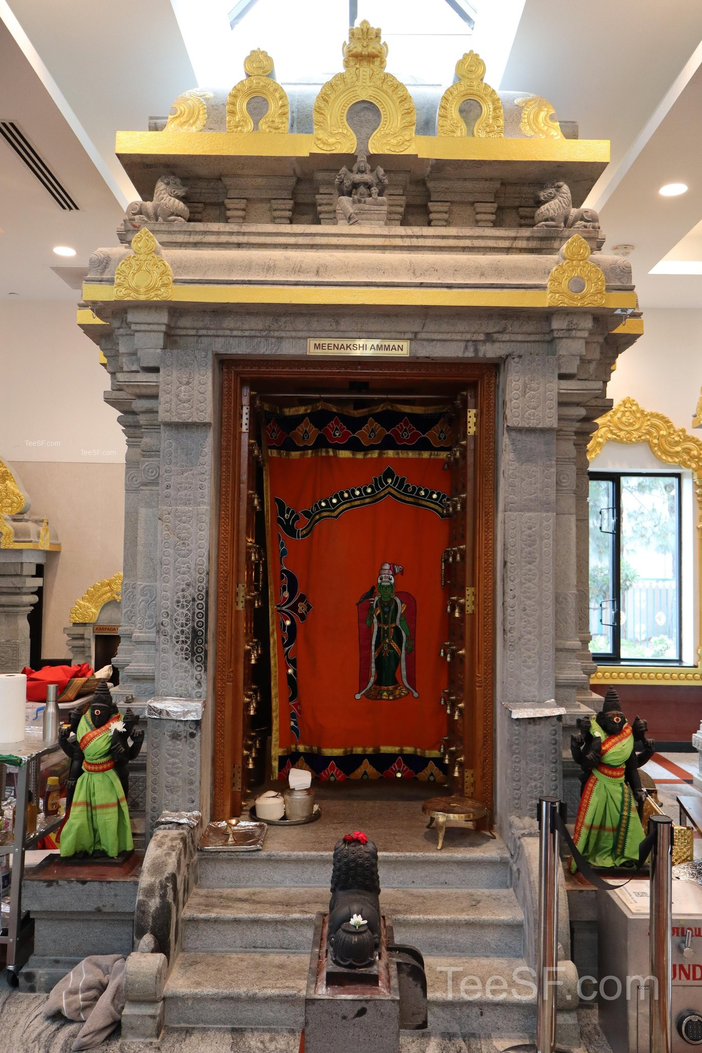 A red temple door shrine framed by stone and gold details.